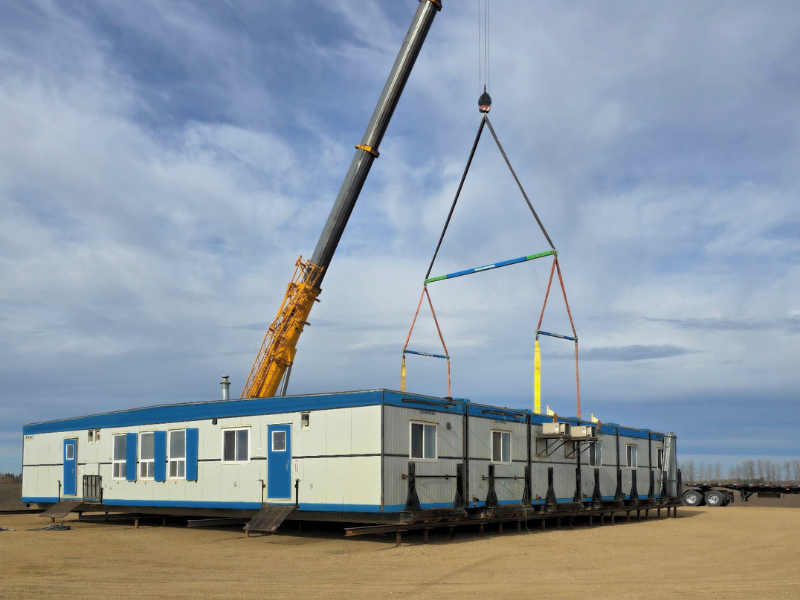 modular dorm craned onto skids with blue sky and dirt foreground