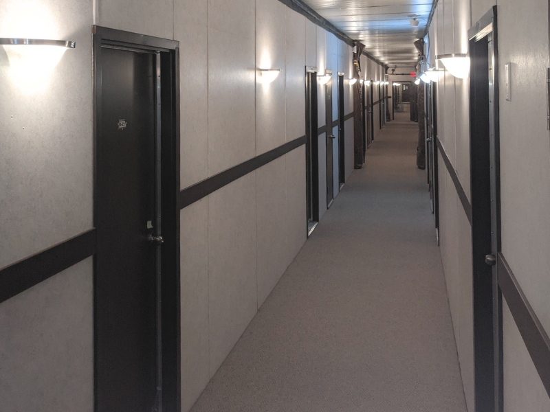 Long oilfield camp modular hallway with brown doors and a taupe carpet