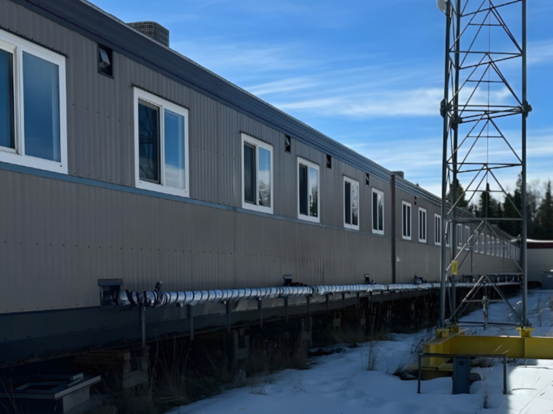 Long row of pre-fab modular dorms exterior with blue sky and snowy ground