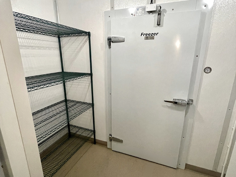 Kitchen freezer door entrance with white walls and taupe flooring