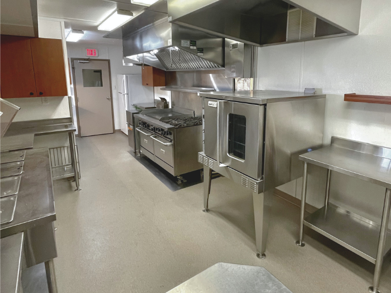 Kitchen modular trailer with commercial appliances with white walls and linoleum flooring