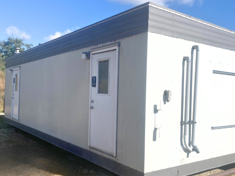 Jack and Jill lavatory modular exterior with blue sky and dirt ground