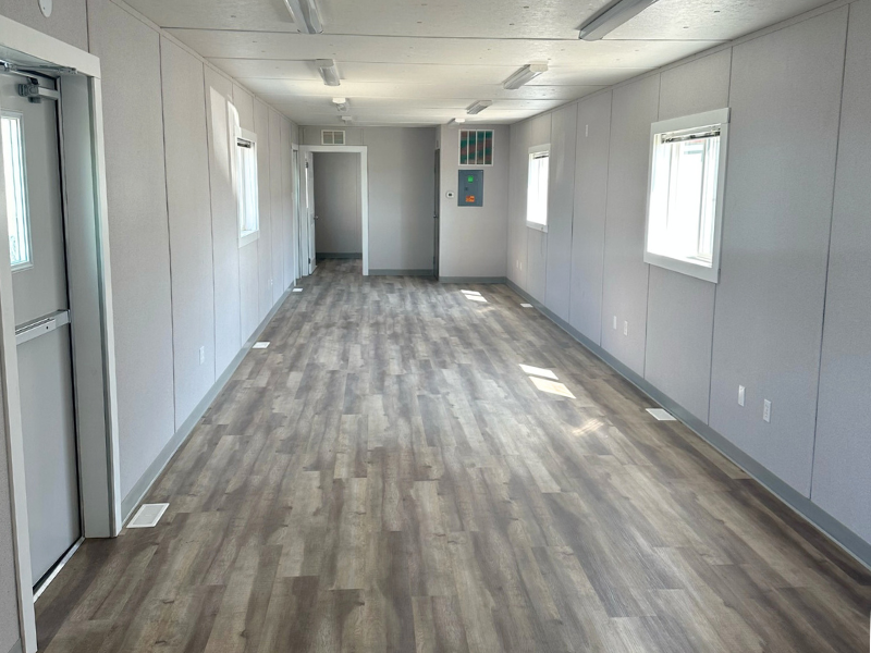 Pre-fab modular office interior with white walls and wood grain flooring